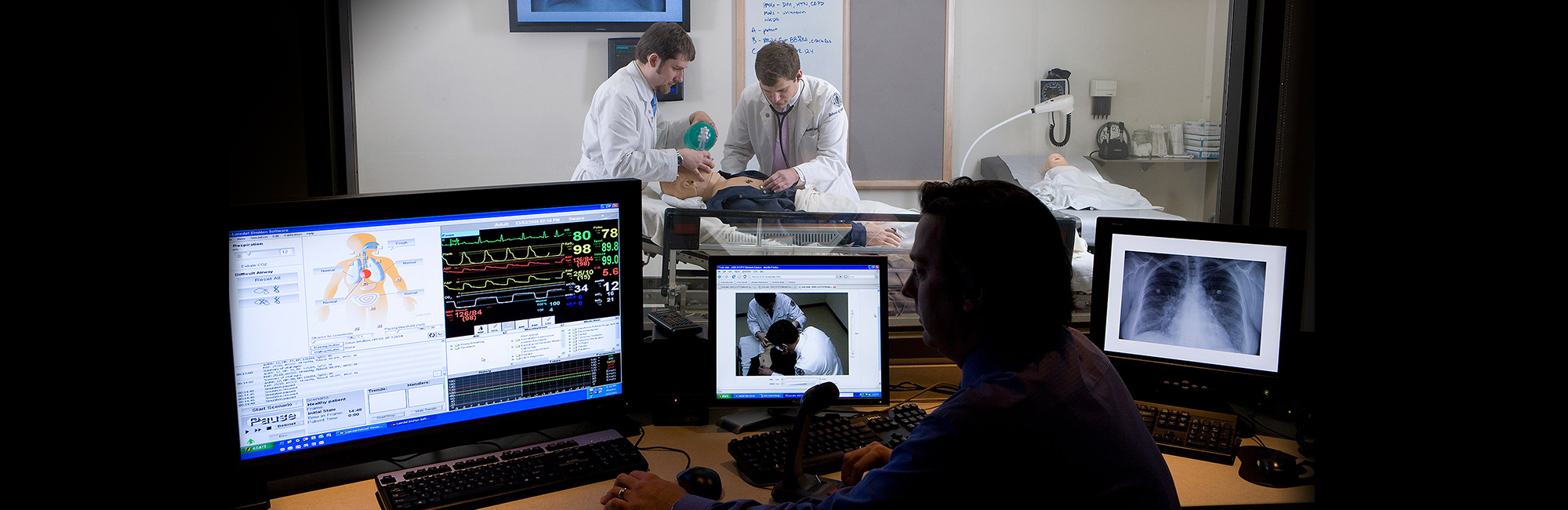 Dr. Thomas Nowicki, director of medical simulation at UConn observes Benjamin Silverberg, a fourth year medical student and Austin Schirmer, a second year medical student