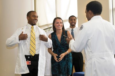 students receiving white coats