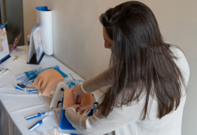 Female student learning at the last Symposium's surgical training fair at Brown University how to do a urology procedure.